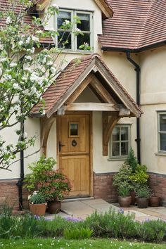 a house with potted plants in front of it and a wooden door on the side