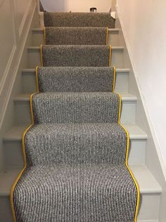 the carpeted stairs are lined with black and white striped rugs, along with yellow trim