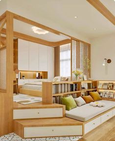 a living room filled with furniture and bookshelves next to a staircase leading up to a bed