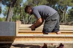 a man is working on building a house in the middle of the woods with wood planks