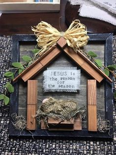 a wooden frame with a nativity scene in the shape of a house on top of a table