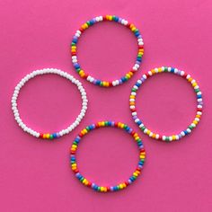 three bracelets with beads on a pink background