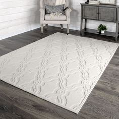 a large white rug with wavy lines on the floor in front of a gray chair