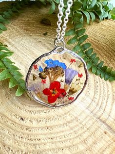 a close up of a necklace on a tree stump with leaves and plants in the background