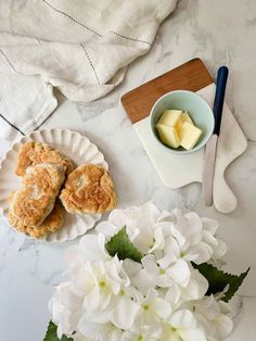 some food is sitting on a plate next to flowers and a bowl with cheese in it