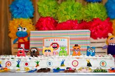 the birthday cake is decorated with colorful paper pom poms and sesame street characters