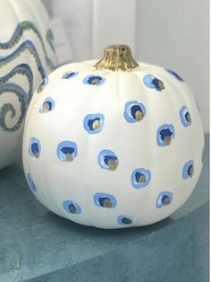 two white pumpkins with blue and gold designs on them sitting next to each other