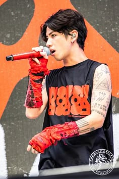 a man with tattoos on his arm holding a microphone