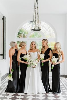 bridesmaids in black and white gowns standing together at the entrance to their wedding