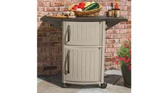 an outdoor kitchen cart with food on top and vegetables in the basket next to it