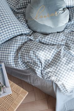 a bed with blue and white checkered sheets, pillows and pictures on the floor