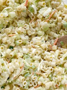 macaroni salad in a white bowl with a wooden spoon