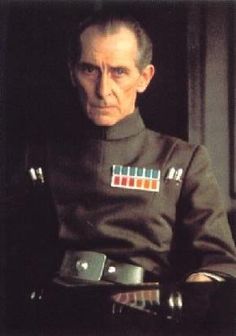 an older man in uniform sitting down with his hands on his hips and looking at the camera