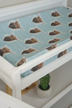 a small white crib with a blue and brown cat print sheet on it's cover