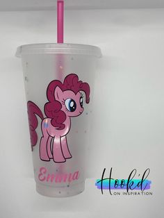 a pink cup with a pony on it and a straw in the bottom that says,