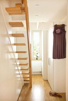 there is a wooden stair case in the hallway next to a window with blinds on it