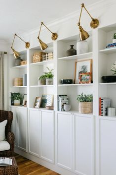 a living room filled with lots of white bookshelves covered in plants and vases