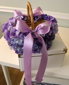 a basket filled with purple flowers sitting on top of a white table next to a box