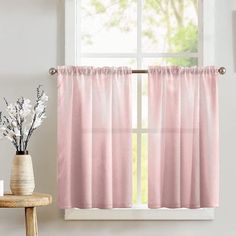 a window with pink curtains next to a vase filled with white flowers and a potted plant