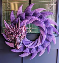 a purple wreath with a dragon's head hanging on the front door to decorate it