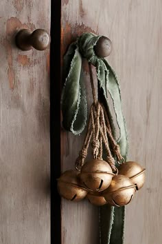 an old door with two bells hanging from it's side and a green scarf on the handle