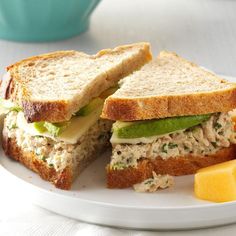 a sandwich cut in half sitting on top of a white plate next to lemon wedges