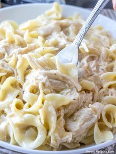 a person holding a fork in a bowl of pasta with meat and cheese on it