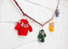 several knitted toys hanging on a white brick wall