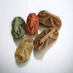 four different colored purses sitting next to each other on a white surface with one bag in the middle