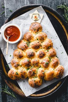 hot cross buns on a plate with dipping sauce and herbs next to it, ready to be eaten