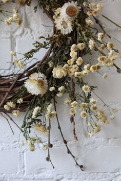 a bunch of flowers that are hanging on a brick wall with white bricks in the background