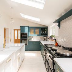 a kitchen with green cabinets and white counter tops, along with a skylight over the stove