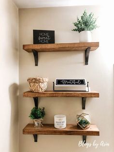 three wooden shelves with signs and plants on them in the corner of a bathroom area