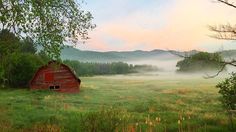 an old red barn in the middle of a field