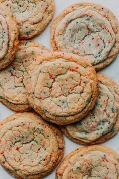 a pile of cookies with sprinkles sitting on top of a white table