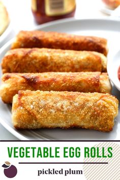 vegetable egg rolls on a white plate with pickled plum and ketchup in the background