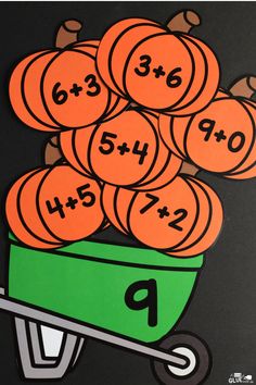 a pile of oranges sitting on top of a wheelbarrow filled with numbers