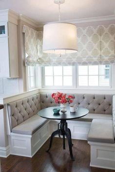 a corner table with two chairs and a bench in front of it, next to a window