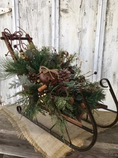 an old fashioned sleigh decorated with evergreen, pine cones and other greenery