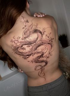 a woman's back with a dragon tattoo on her stomach and the upper part of her body covered in flowers