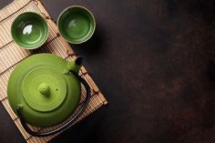 a green teapot and two cups on a bamboo mat - stock photo - images