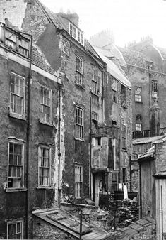 black and white photograph of old buildings in an alleyway with broken windows on the side