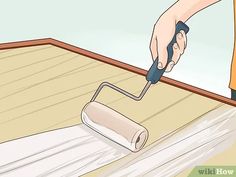 a person using a paint roller on the floor with a wooden plank in front of them