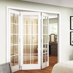 a bedroom with white walls and wooden floors has french doors open to let in light