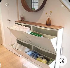 an open drawer in the corner of a room with a mirror on the wall above it