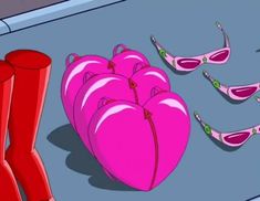 pink boots are sitting on the ground next to a heart - shaped bag and several pairs of red high heeled shoes