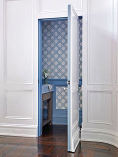 an open door in a room with white walls and wood flooring on the side