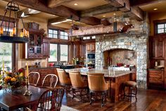 a large kitchen and dining room with wood flooring, stone fireplace in the center