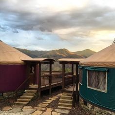 two yurts are set up in the mountains with steps leading to them and there is no one outside