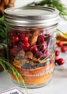 a jar filled with cranberries and cinnamons on top of a white table